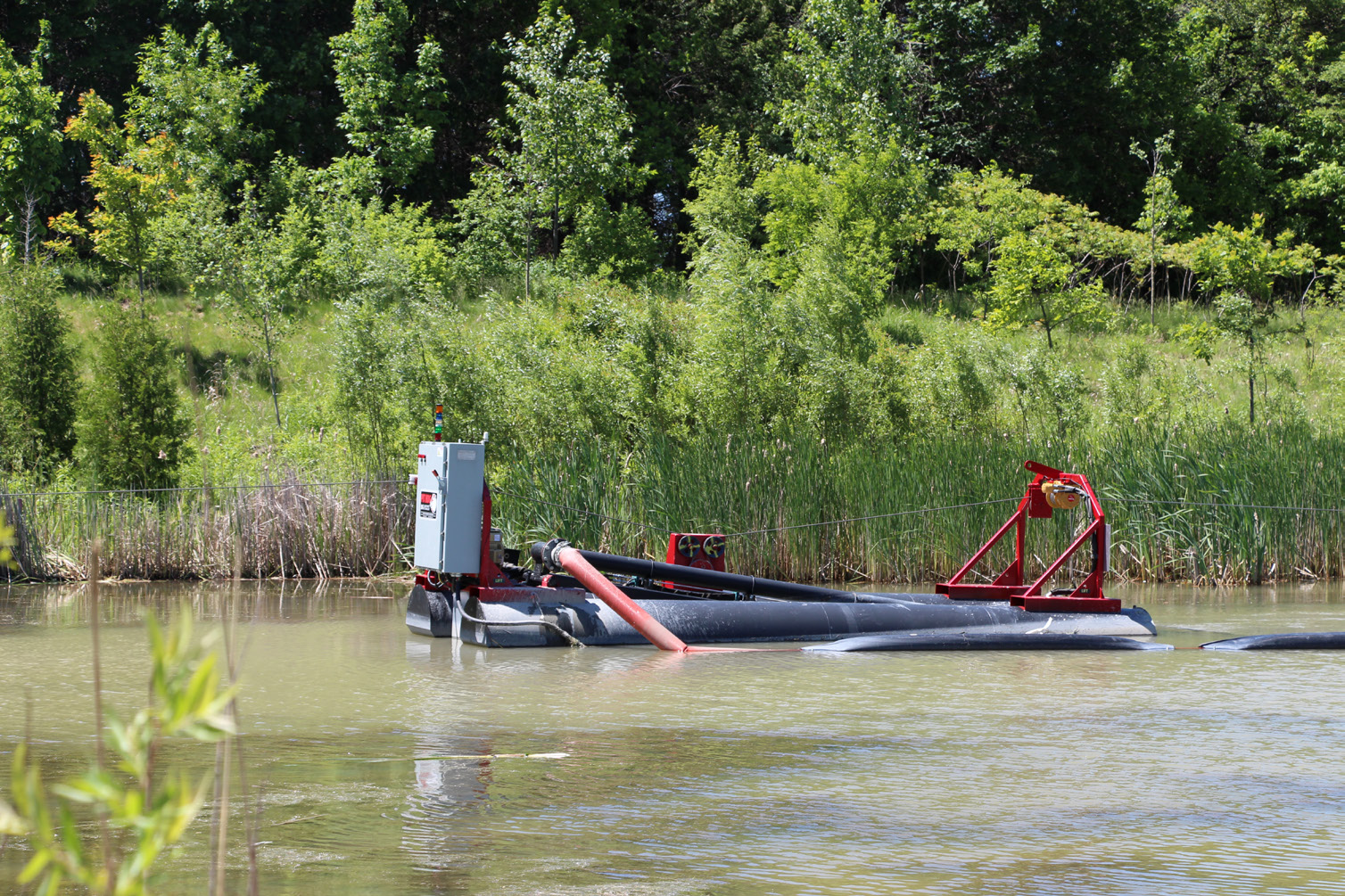Figure 4. Pit Hog™ dredge operating in Pond 4. The dredge is floating in the pond, with intake and discharge hoses attached.